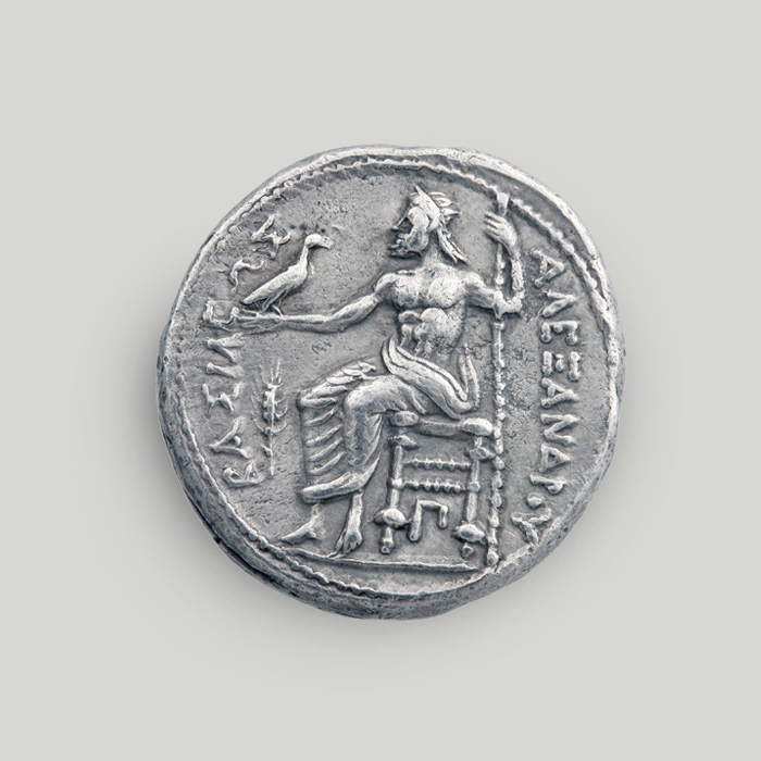 Οπίσθια όψη αργυρού τετράδραχμου Μεγάλου Αλεξάνδρου με τον Δία σε θρόνο να κρατάει αετό και σκήπτρο.   Οπίσθια όψη αργυρού τετράδραχμου Μεγάλου Αλεξάνδρου, Μακεδονία