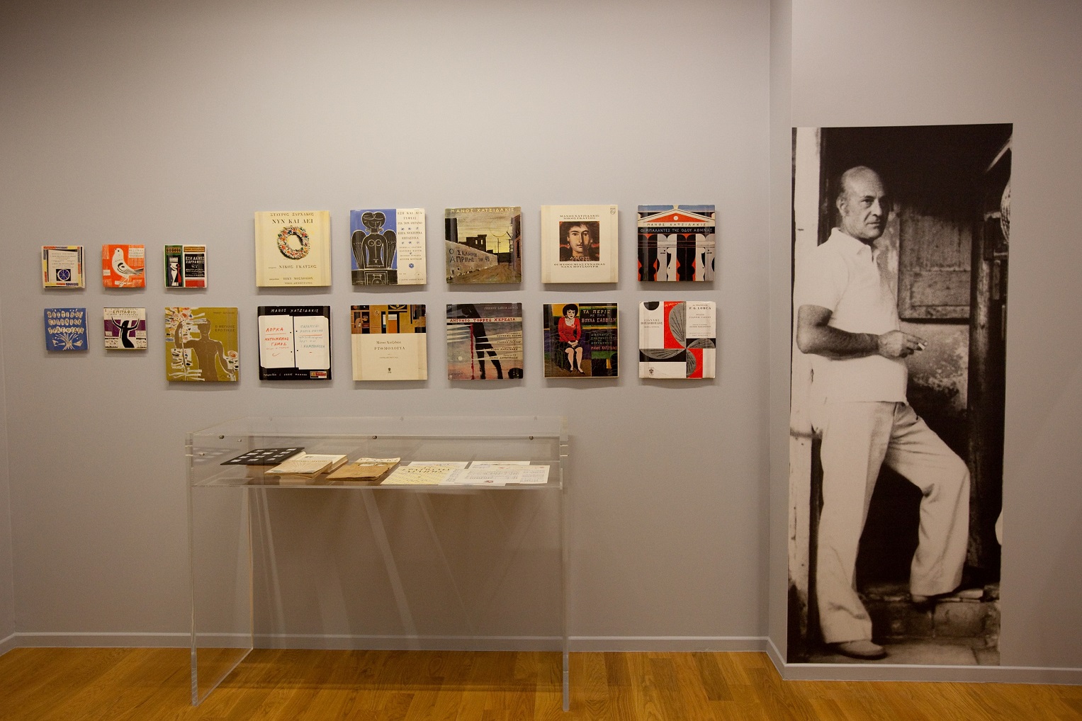 A picture of Yannis Moralis along with books he illustrated.  Yannis Moralis and books, exhibition “Yannis Moralis. Theatre-Music-Poetry”