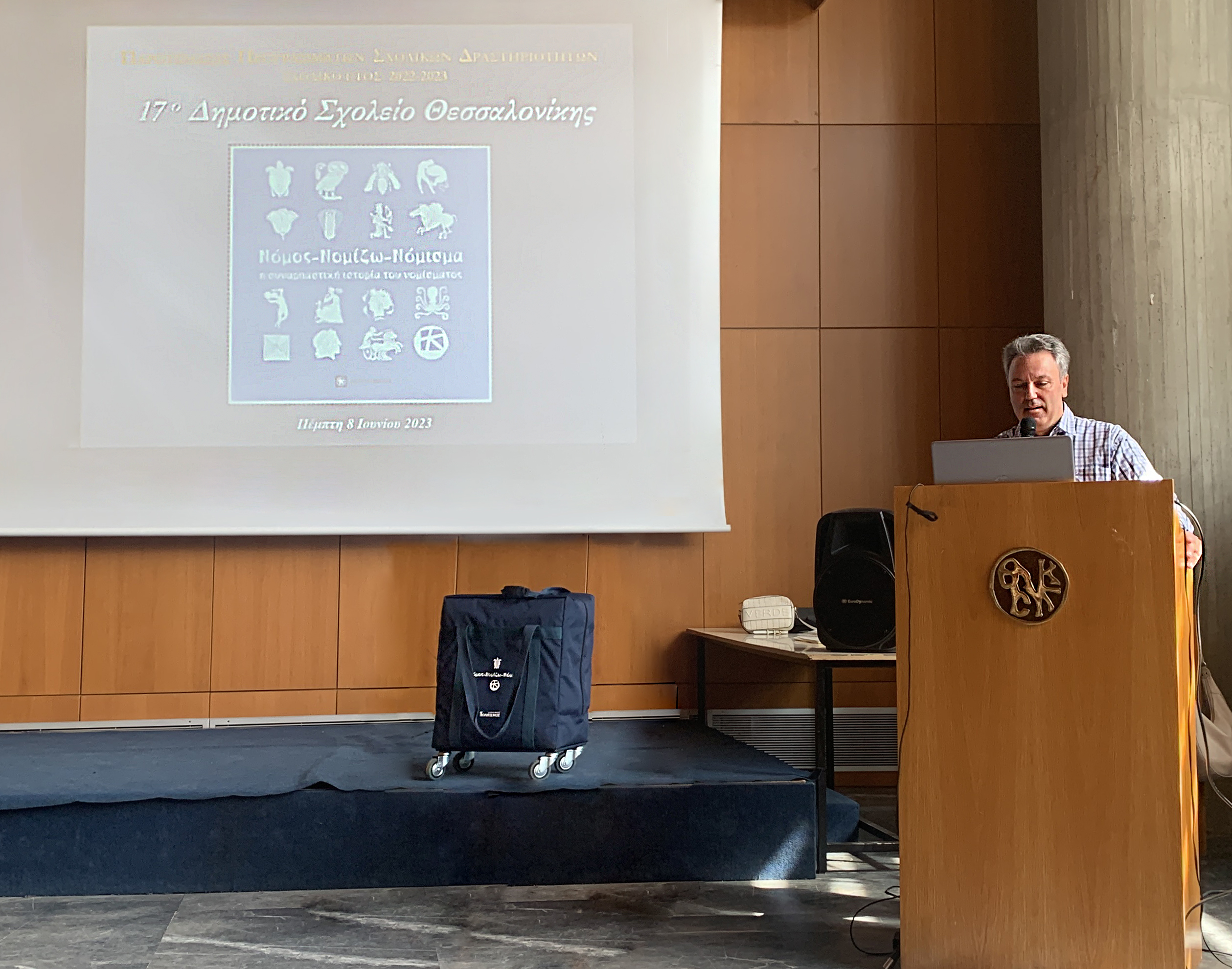 The Principal of the 17th Primary School of Thessaloniki, Mr Dimitris Tsintaris, on the podium and a video projection on the left.  Highlight from the event in Thessaloniki