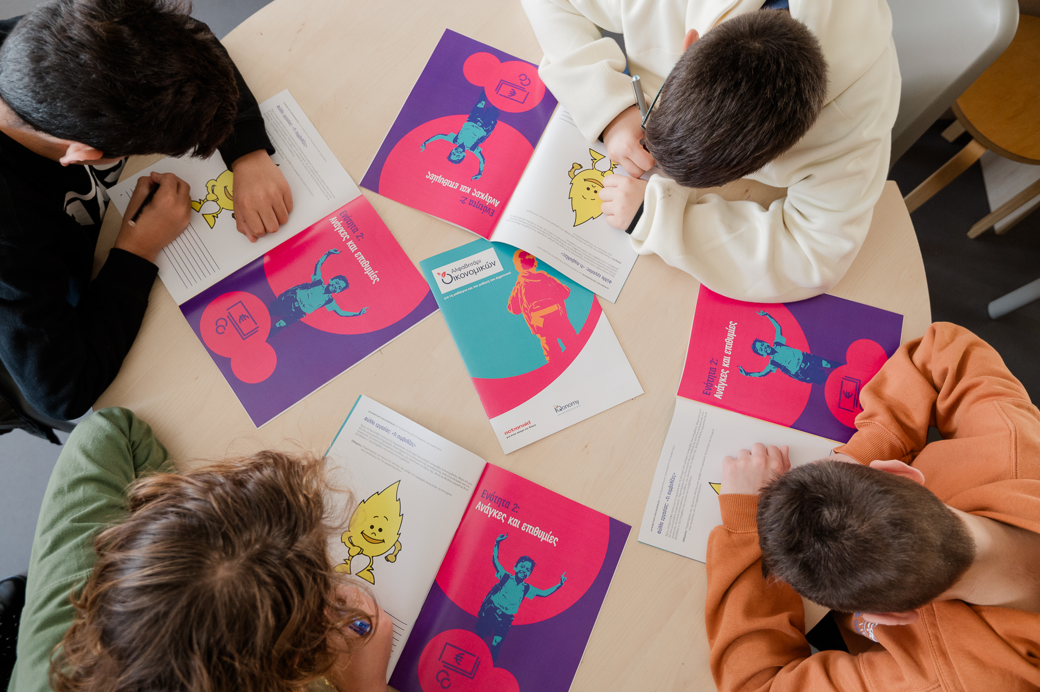 4 children around a wooden table filling in the ABCs of Financials workbook. Highlight from the presentation
