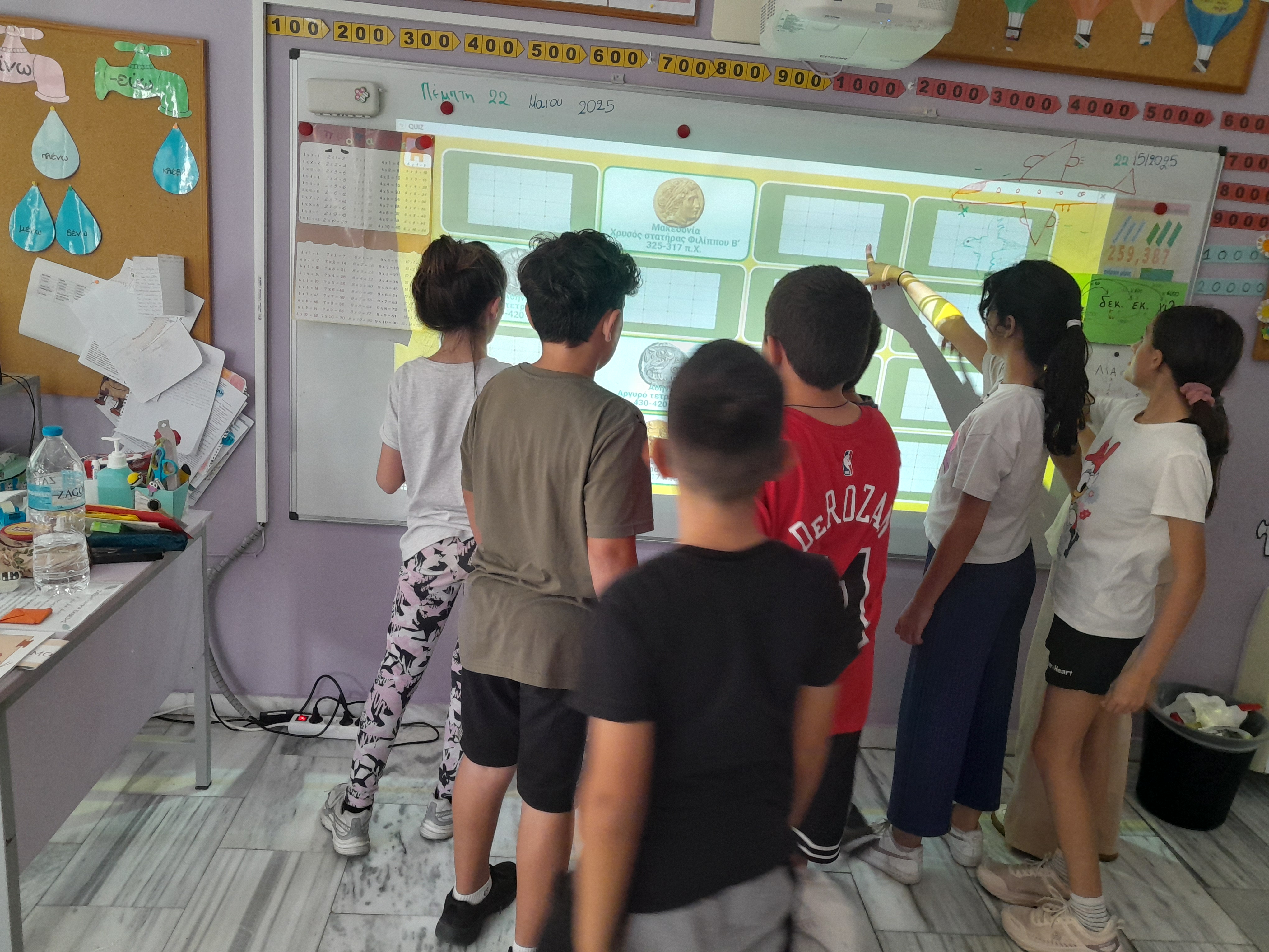Children in front of a board displaying a slide with a programme activity. Snapshot from educational programme
