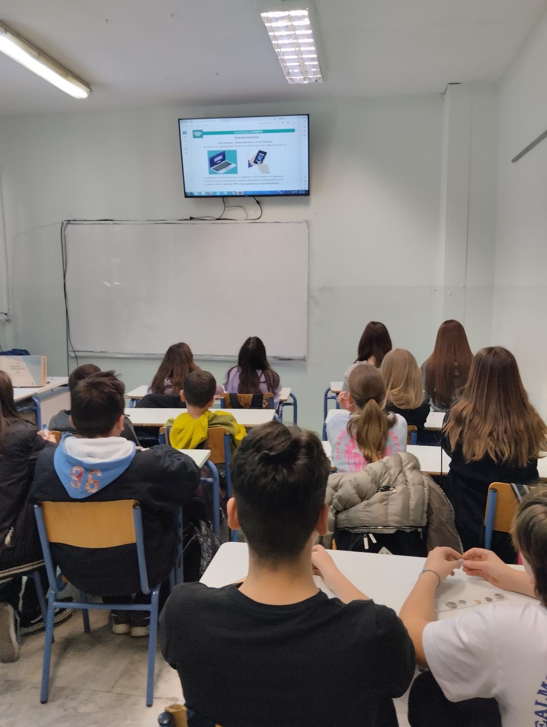 Students sitting at their desks, watching an educational video on a TV screen. Snapshot from educational programme