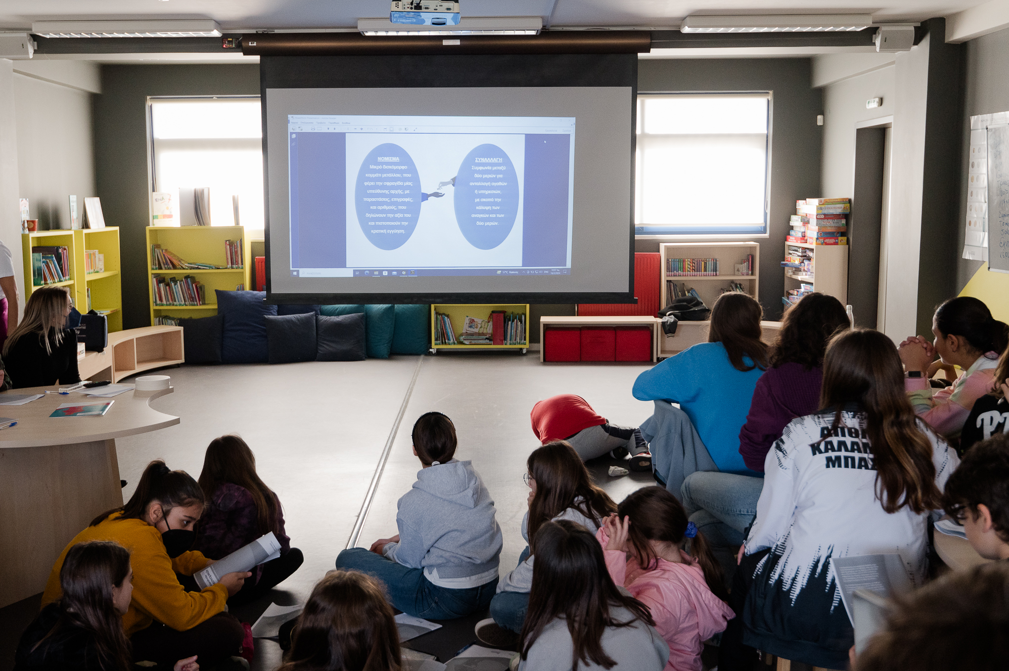 Children sitting on the floor and on chairs watching the presentation on a projector.  Highlight from the presentation