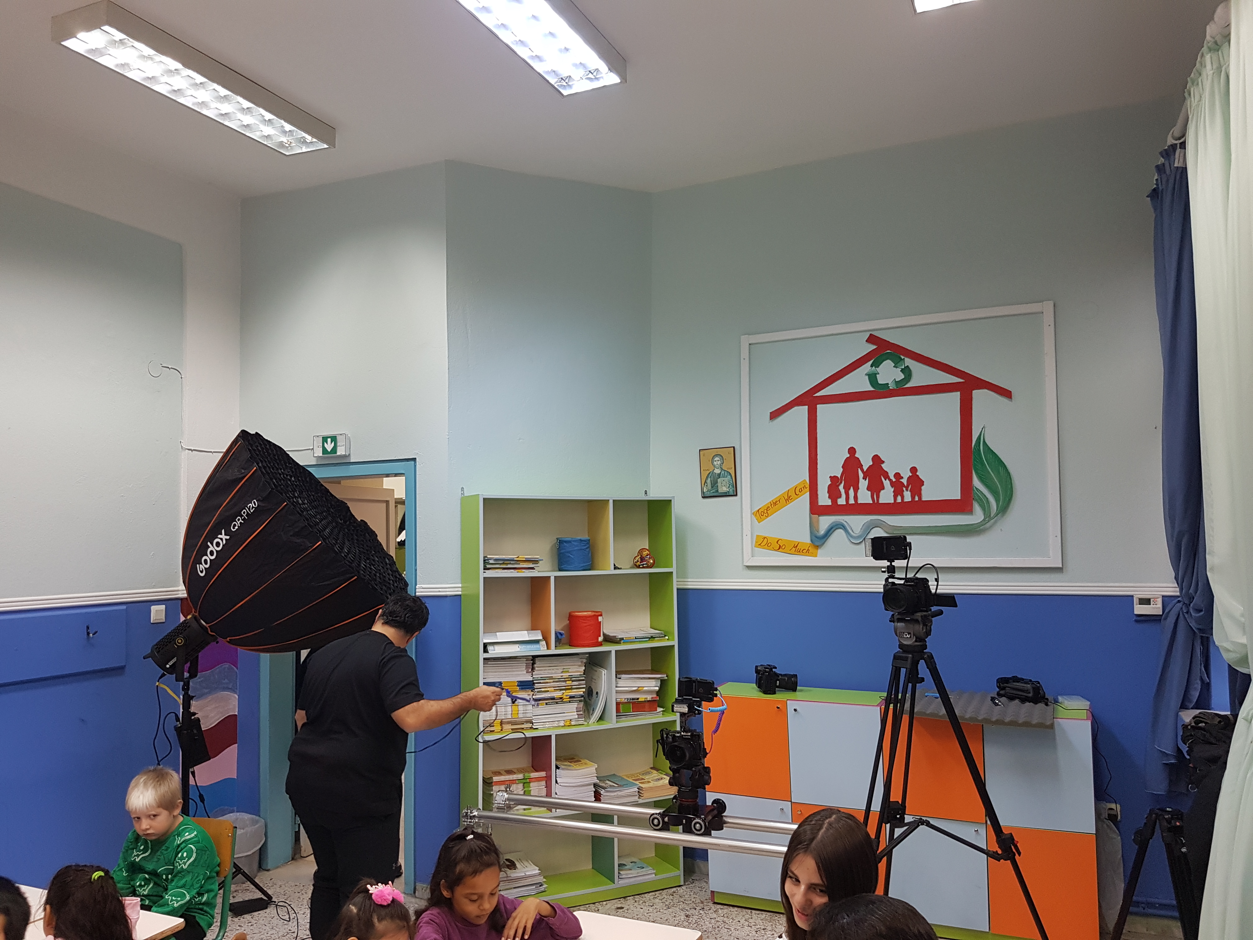 School class with recording equipment. Students sitting at their desk in the front and a cameraman in the back.  “Currency and Transactions” museum kit, Kouloura Primary School