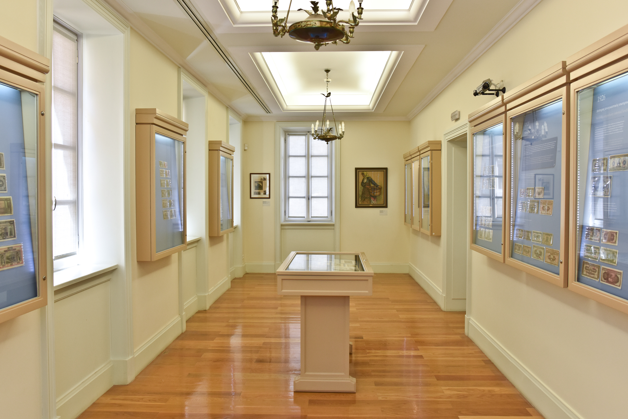 Hall at the Banknote Museum of Ionian Bank with coins in display cases and windows.