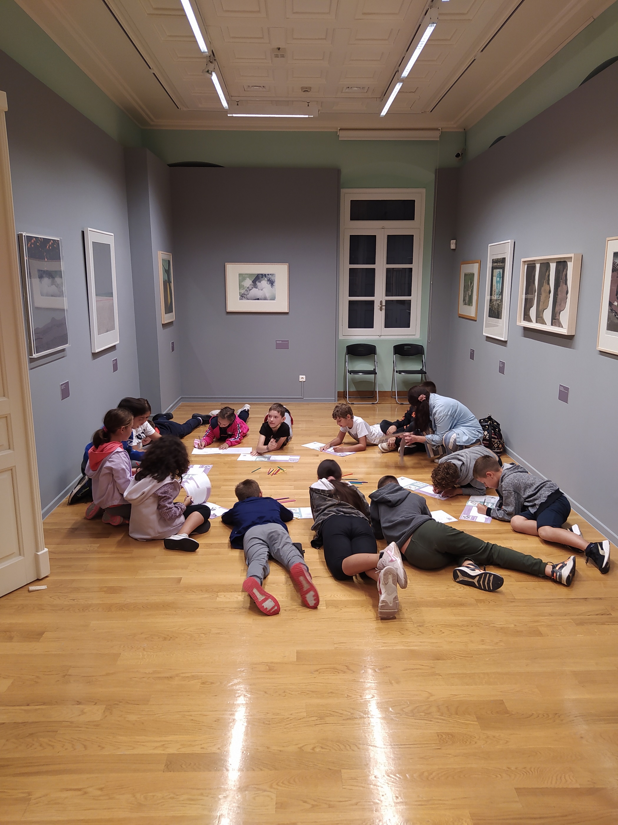 Photo of the exhibition space with students on the floor.  Guided tours at the Alpha Bank Cultural Centre in Nafplio