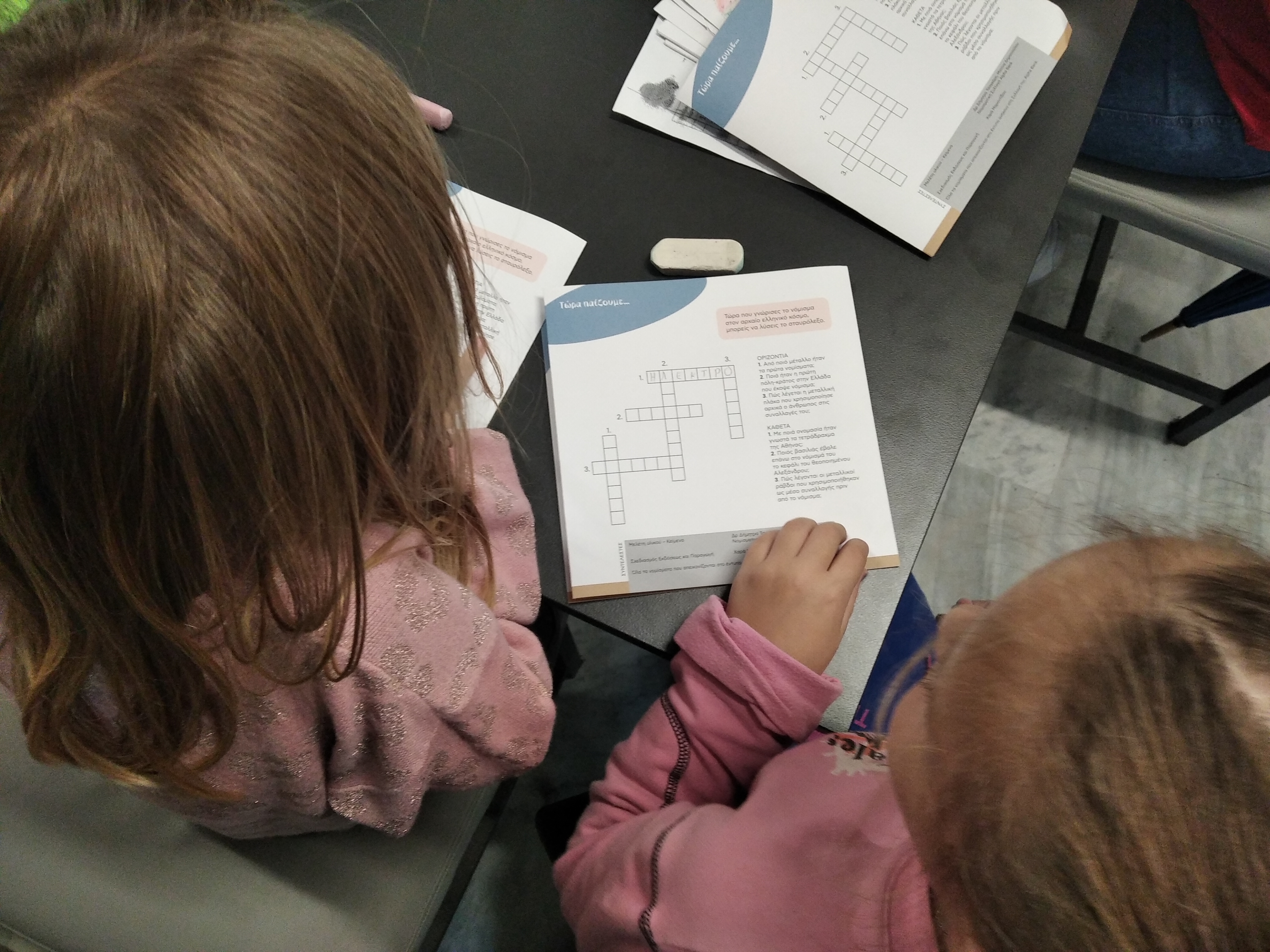 2 girls solving a crossword puzzle included in a programme brochure. Snapshot from educational programme