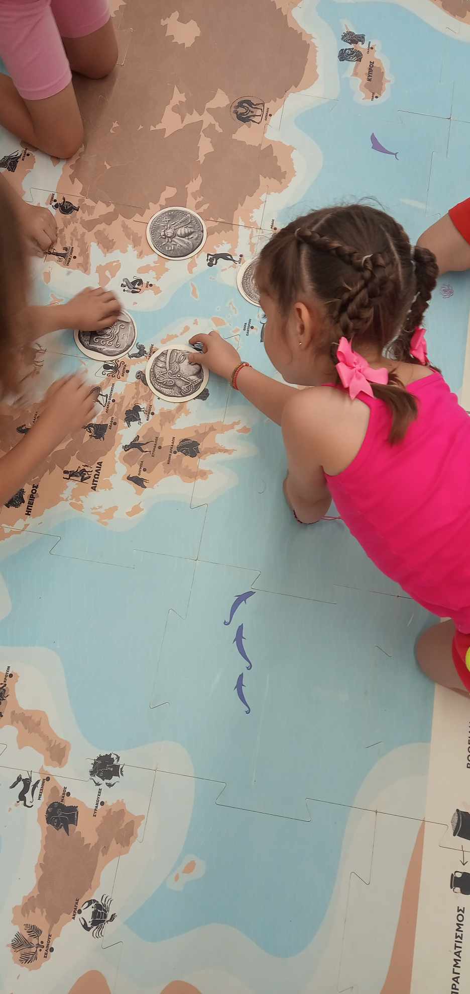 Children place coin cards on a jigsaw puzzle-like floor map. Highlight from the programme
