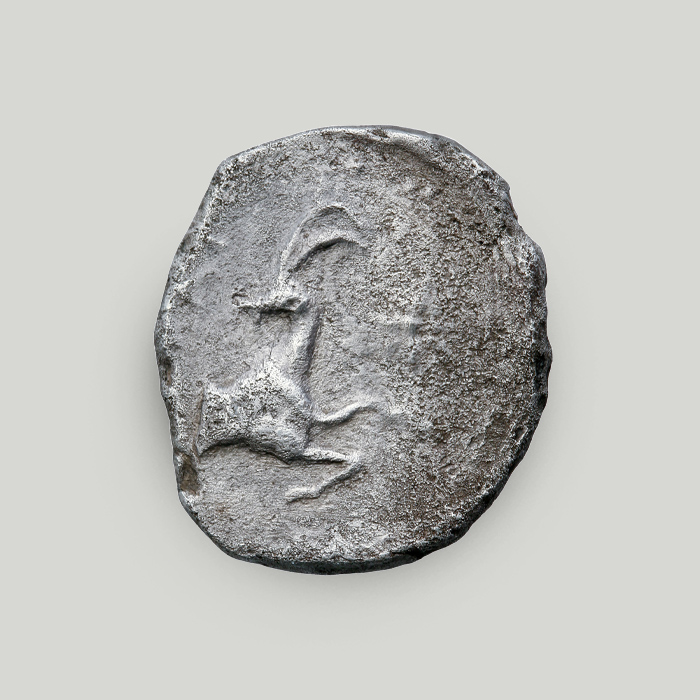 Silver coin depicting the front part of a mountain goat running to the right, its head reverted.  Silver stater, Praesos