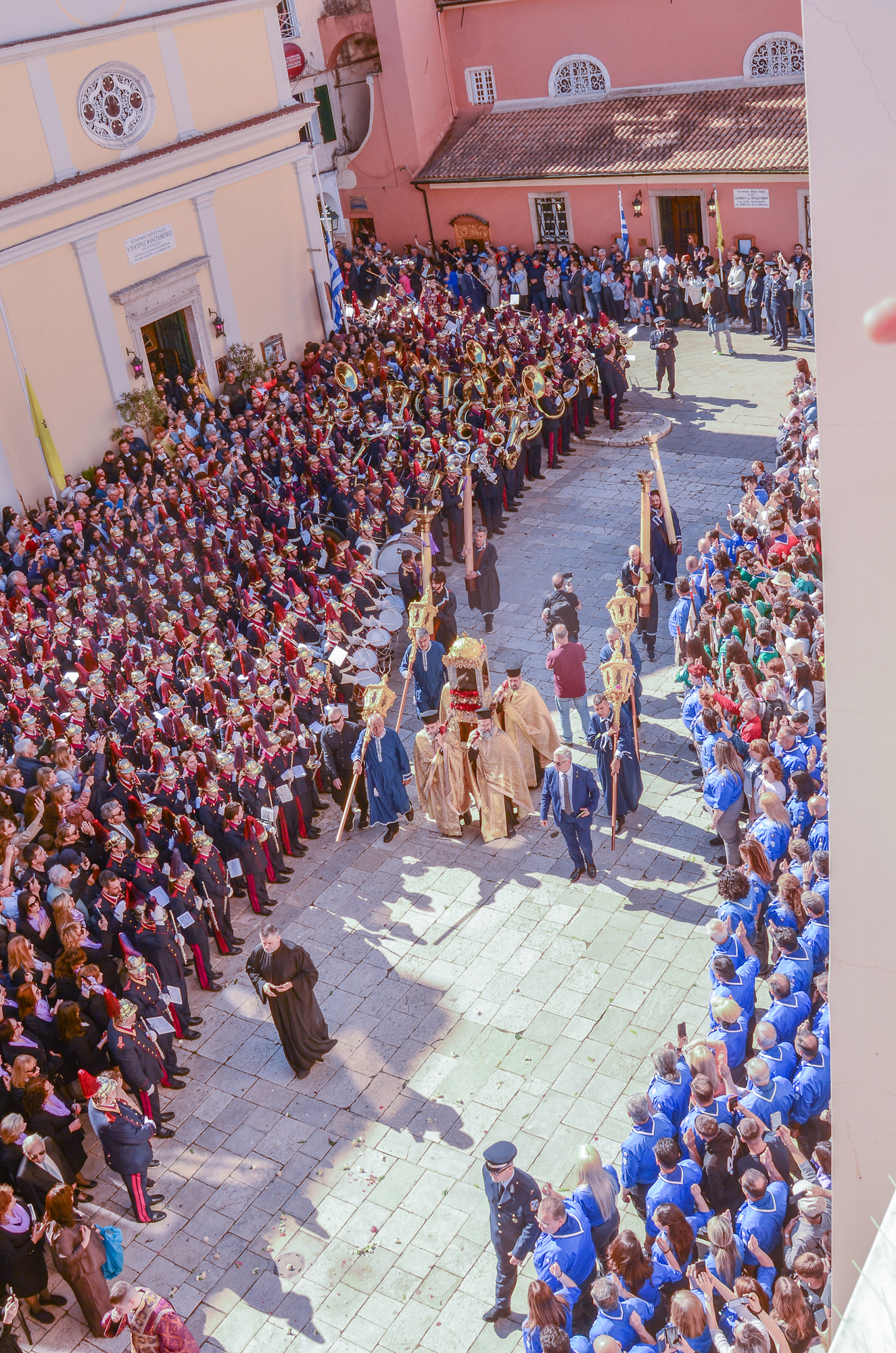 A religious procession carrying the Saint’s relics along a pedestrian street among philharmonic bands and a crowd of people. The procession of Saint Spyridon’s relics