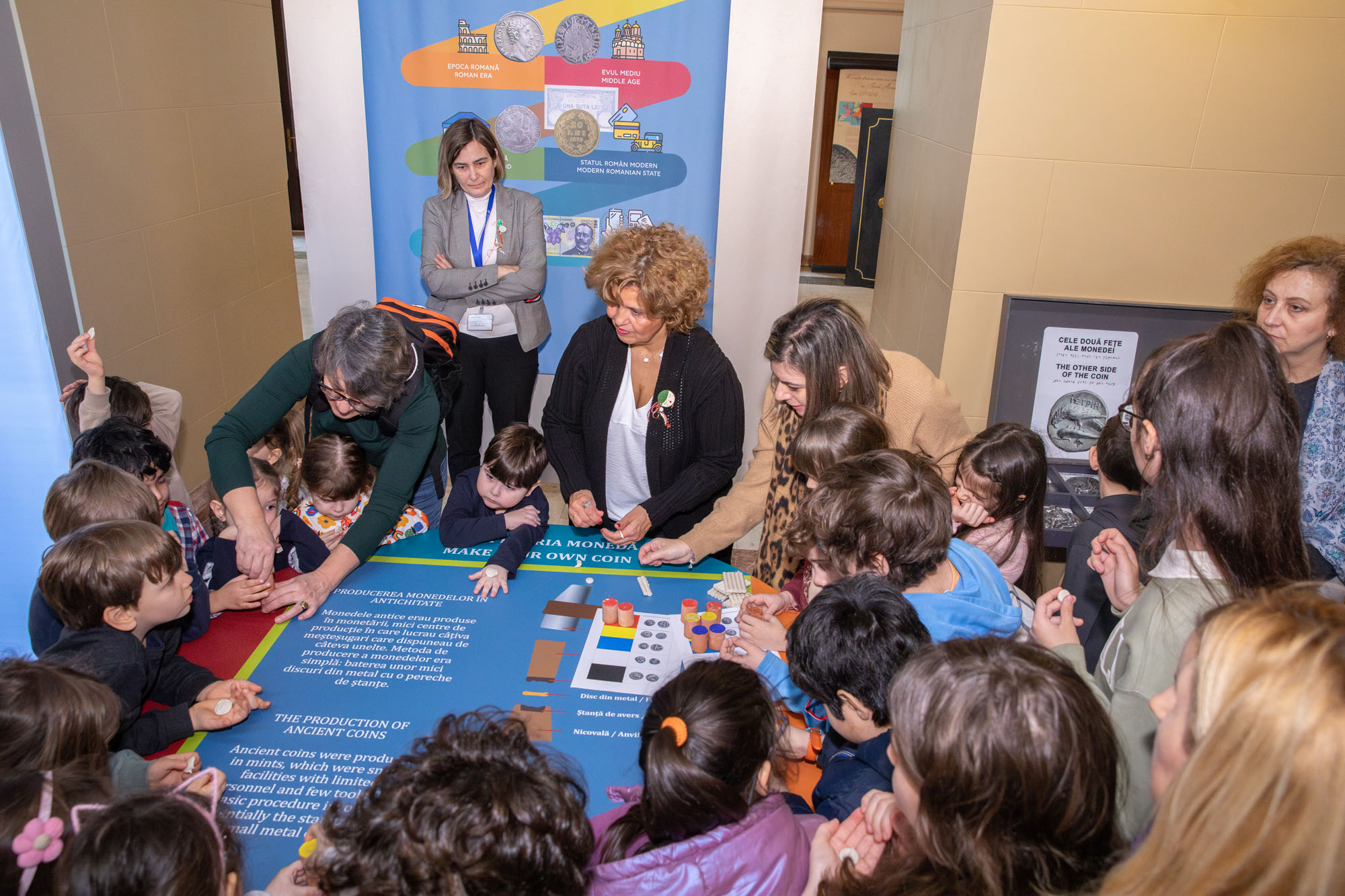 Children in a circle making coins with modelling clay, guided by Ms Dimitra Tsangari. Highlight from a creative activity