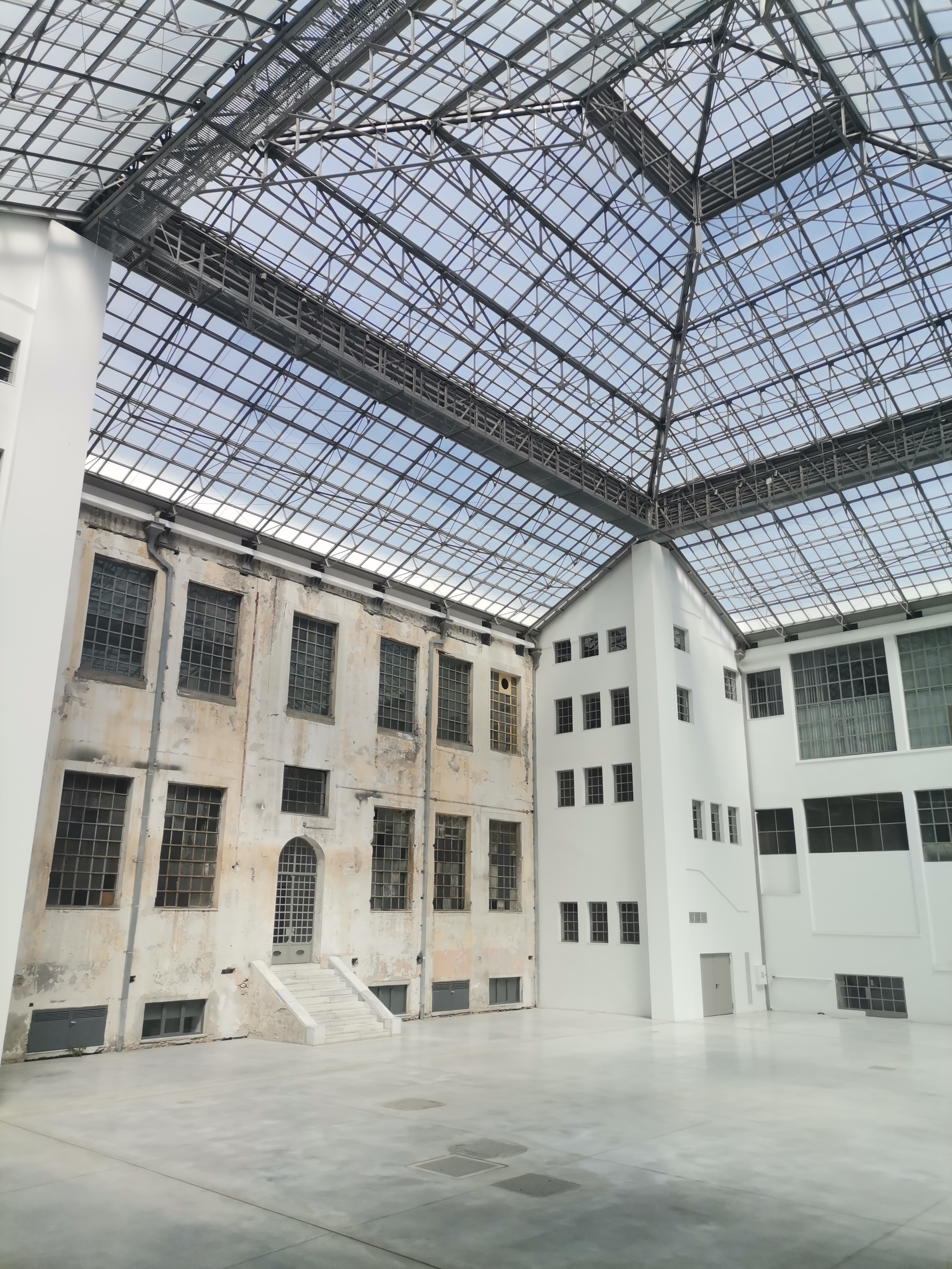 The atrium of the former Public Tobacco Factory. White walls with large windows and a glass roof above. Inside view of the former Public Tobacco Factory