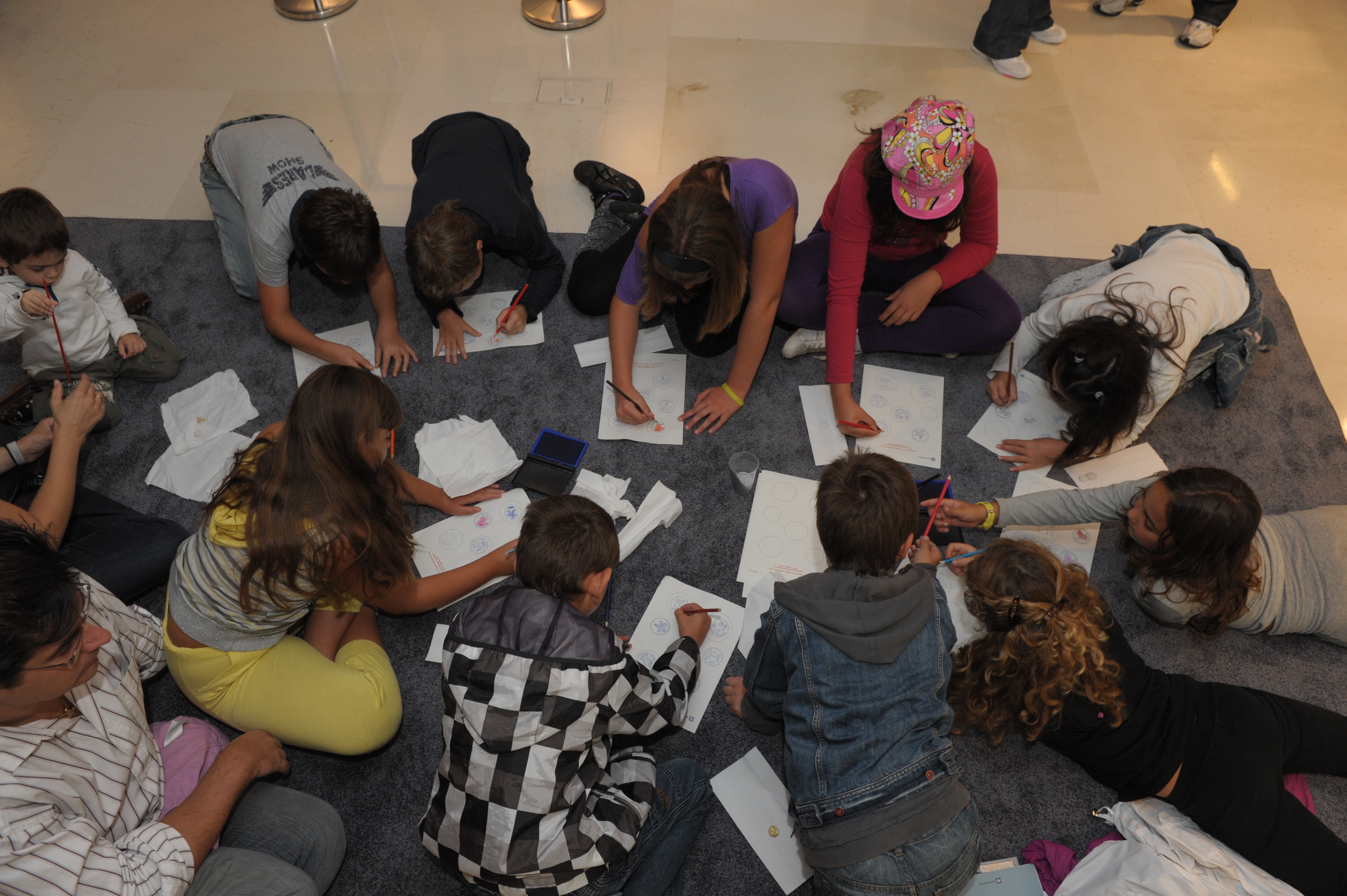 Παιδιά ζωγραφίζουν στο πάτωμα σε εκπαιδευτική δράση στο πλαίσιο της έκθεσης.  Εκπαιδευτική δράση «Μέγας Αλέξανδρος. Από τη γη της Μακεδονίας έως τα πέρατα της οικουμένης»