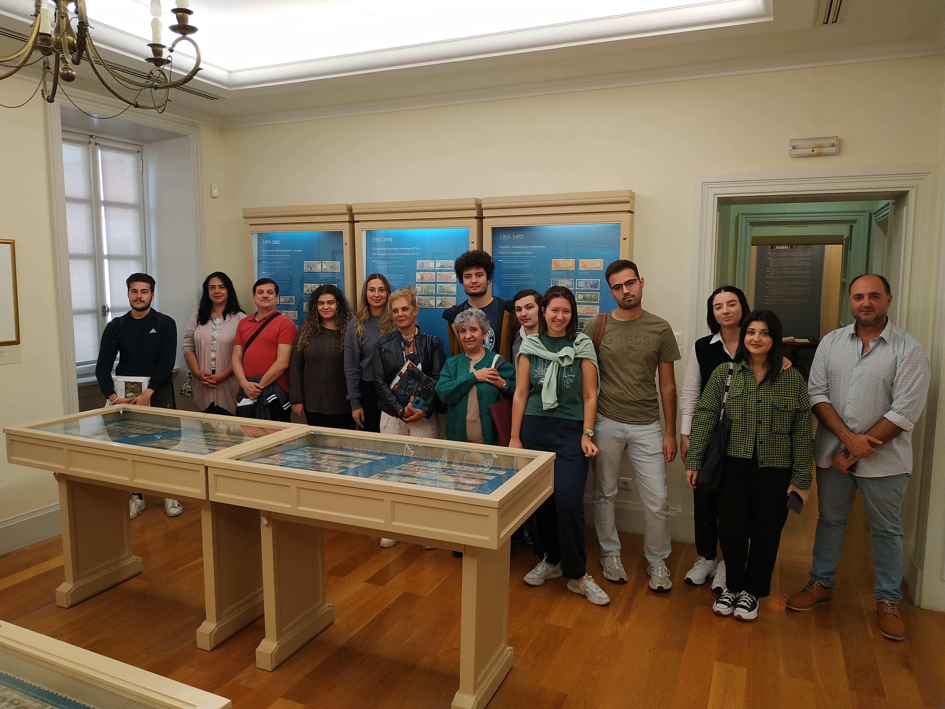 A professor and his students in front of a display case with coins at the Banknote Museum. Group photo