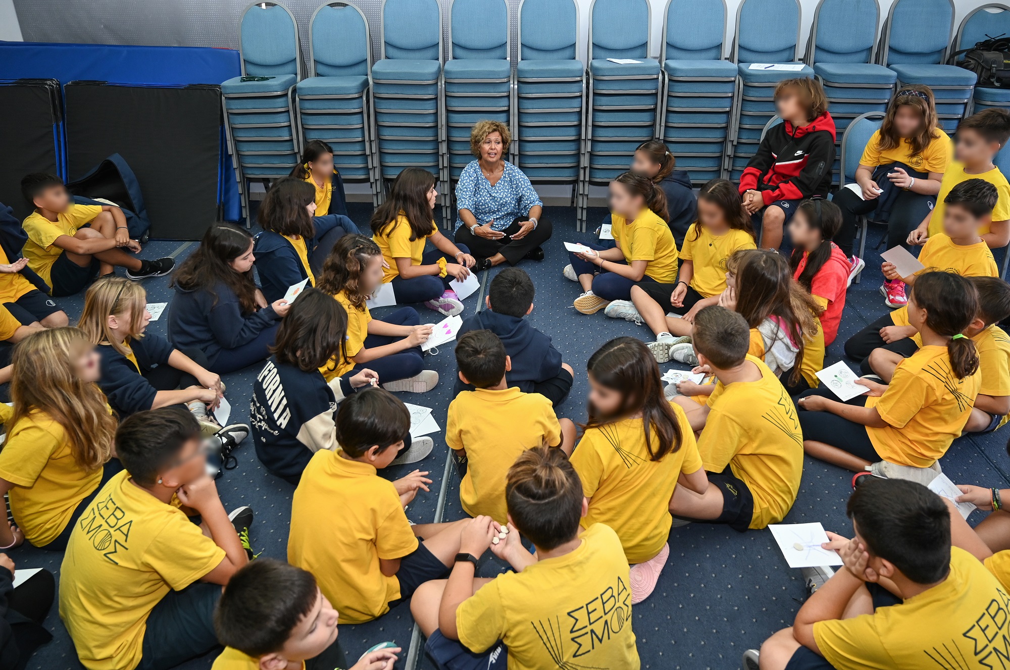 Ms Tsangari sitting on the floor talking to students seated all around her.  Highlight from the presentation