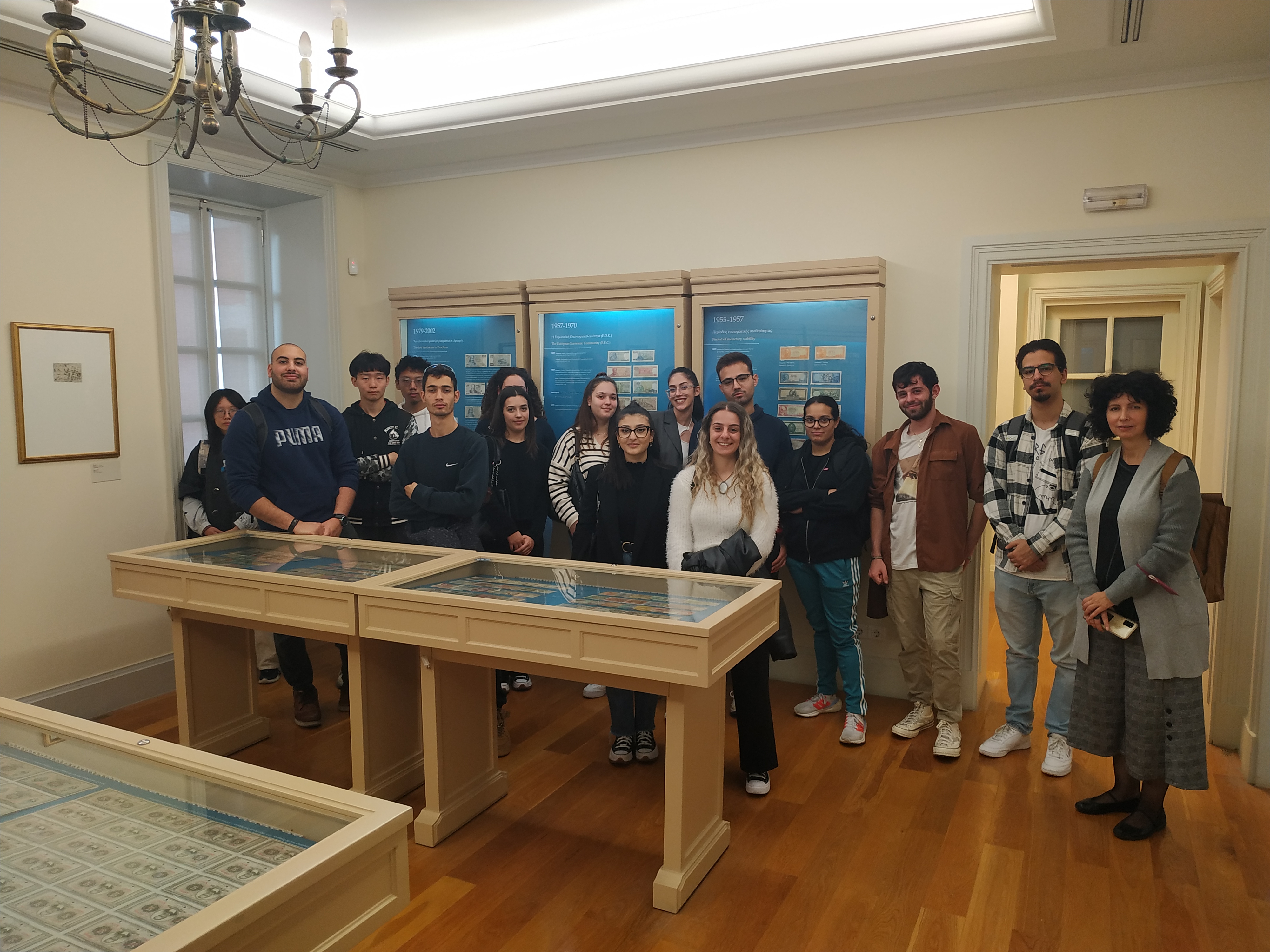 A professor and her students in front of a display case with coins at the Banknote Museum. Group photo
