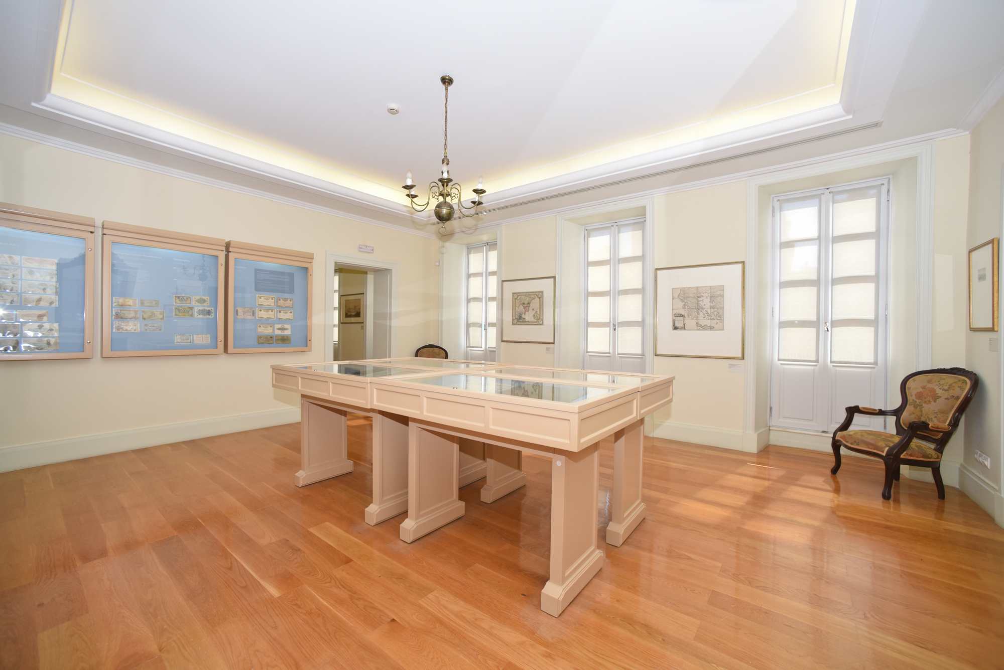 Hall at the Banknote Museum of Ionian Bank with coins in display cases and maps.