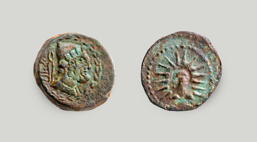 Left: side with head of Hephaestus in profile and tongs; right: side with head of Helios (Sun).  The two sides of the bronze coin from Malaga