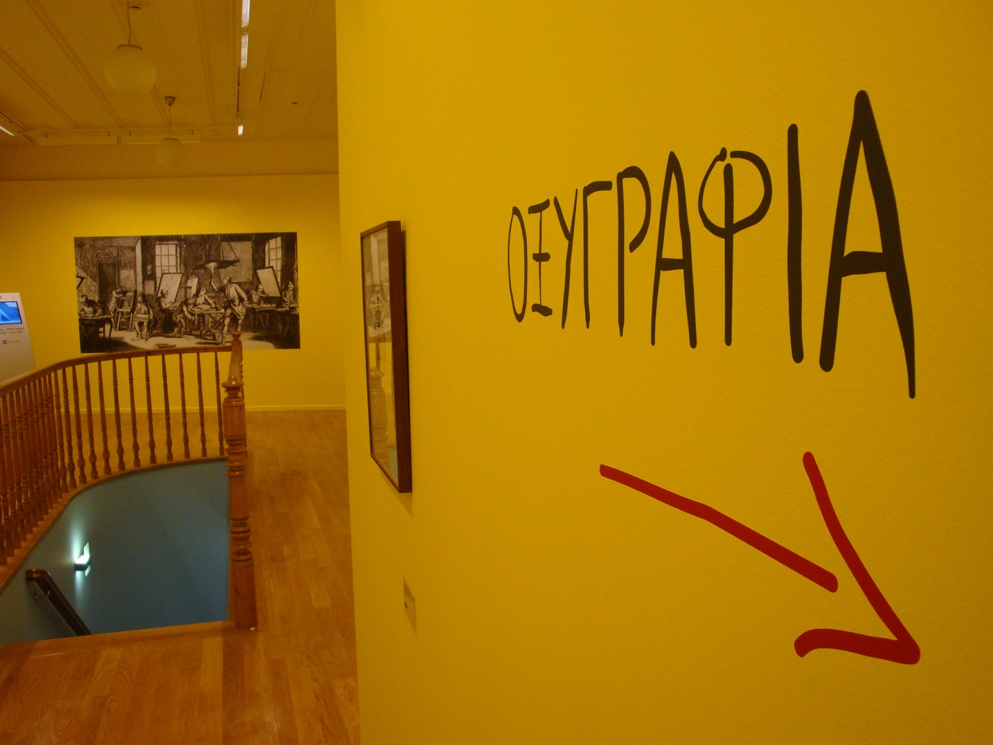 Prints from the exhibition with the word “AQUATINT” on the wall and a pointer arrow below it.  Part of the exhibition “Printmaking and its techniques”