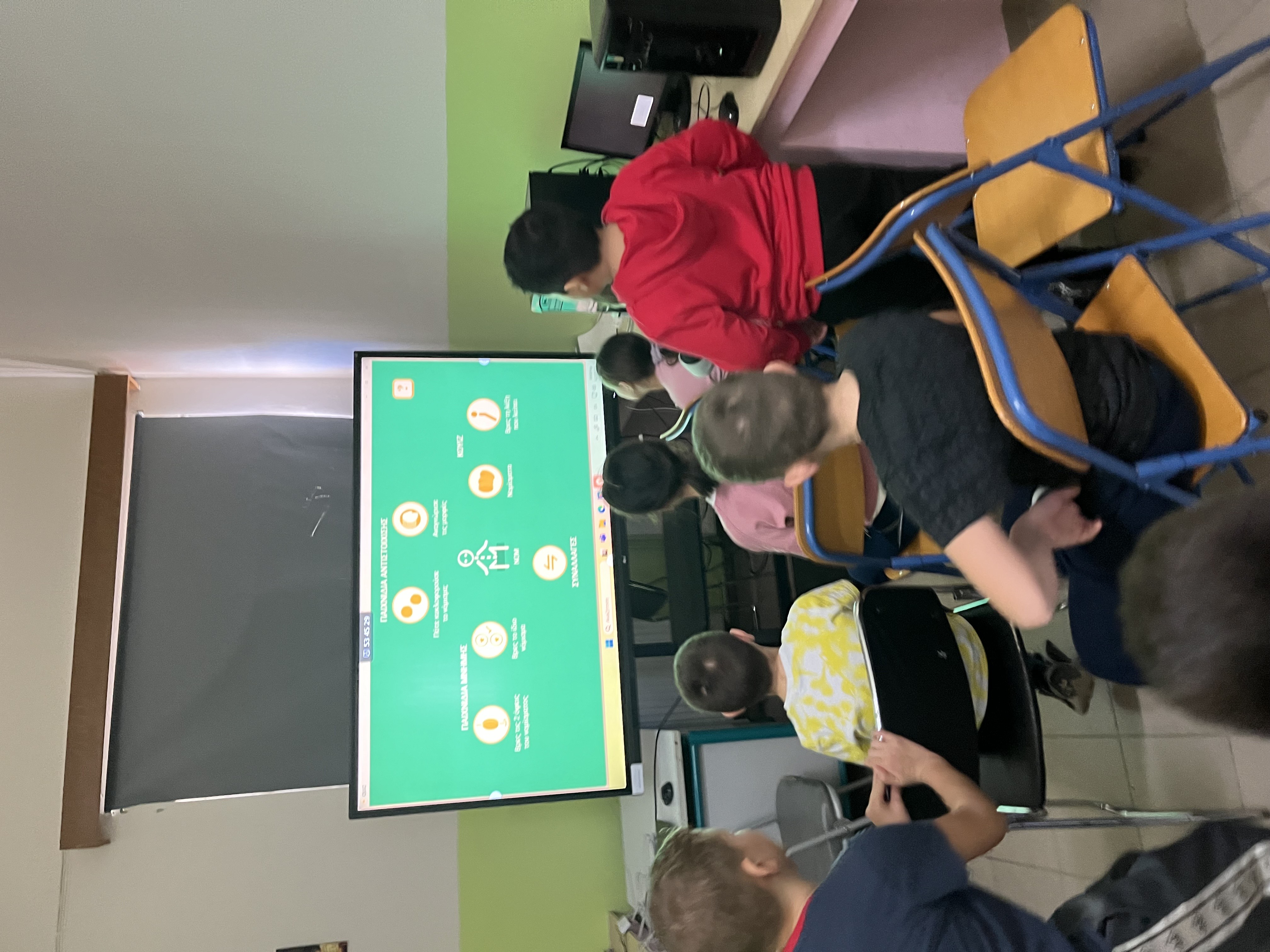 Children seated in front of a screen displaying educational material. Snapshot from educational programme