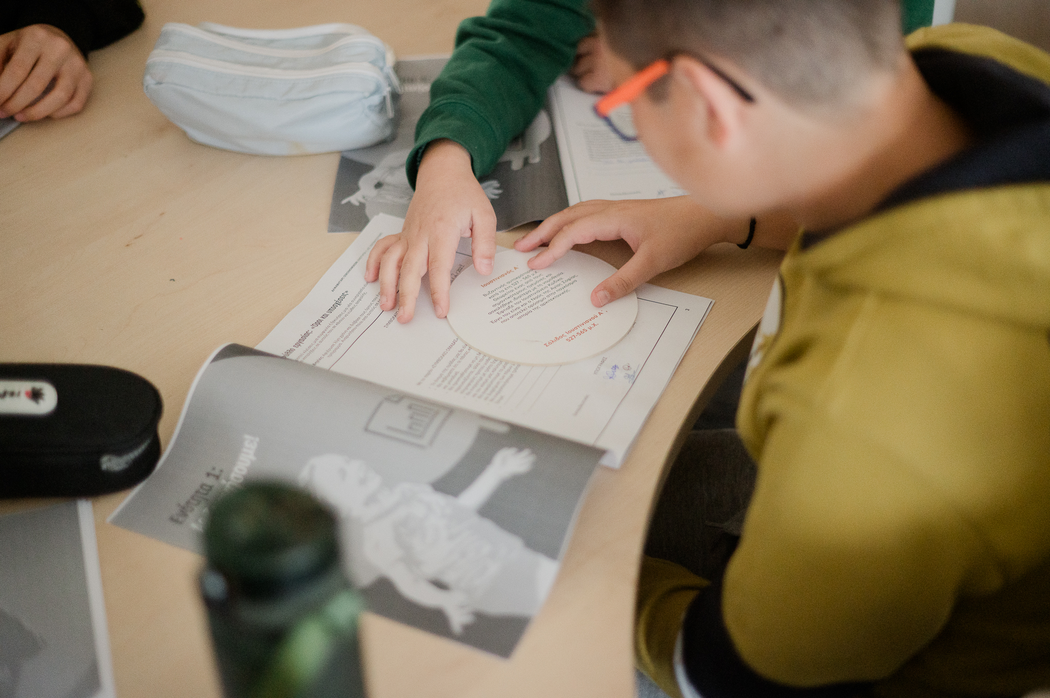 Child at a wooden table reading an educational card about a Byzantine coin. Highlight from the presentation