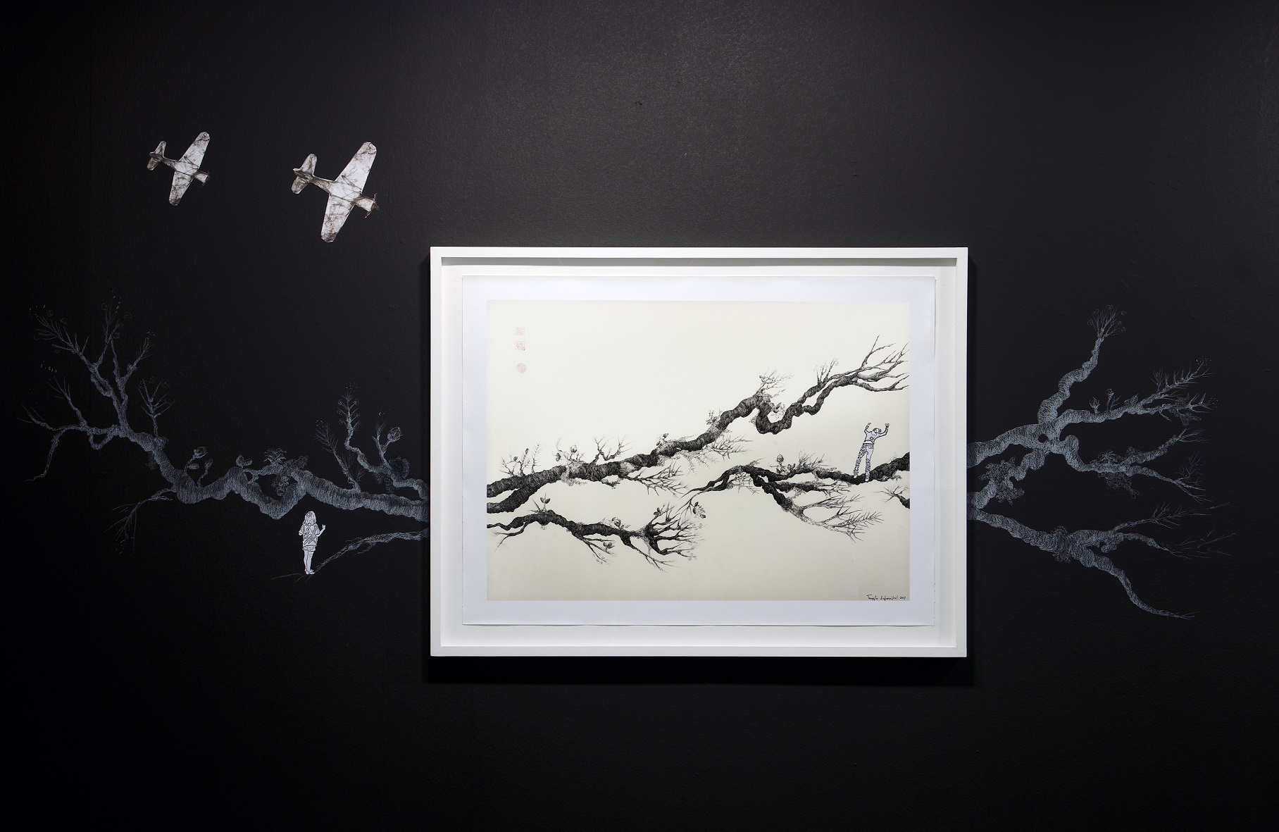 A print from the exhibition Digitals with tree branches, warplanes and a human figure.  Print from the exhibition “Digitals”